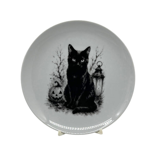 6.25 inch black cat Halloween coupe plate with jack-o’-lantern, lantern, bare branches and black-and-white spooky artwork